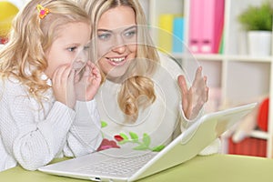 Mother with little daughter using laptop