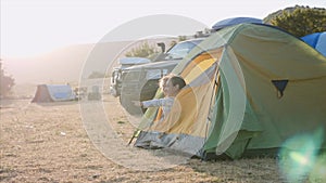 Mother with little daughter wakes up and looks out from tourist tent