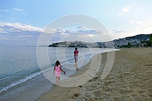 mother and little daughter walk along the seashore