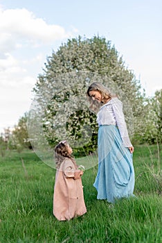 A mother with a little daughter on a walk among a green meadow