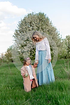 A mother with a little daughter on a walk among a green meadow