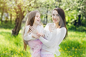 Mother and a little daughter walk in the spring blooming Apple