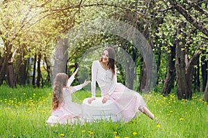 Mother and a little daughter walk in the spring blooming Apple