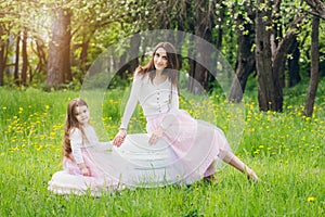 Mother and a little daughter walk in the spring blooming Apple