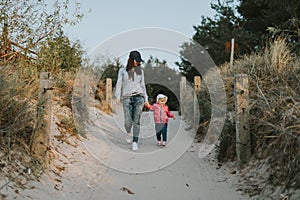 Mother and little daughter walking on the beach