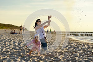 Mother and little daughter walking on the beach