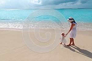 mother and little daughter walking on beach