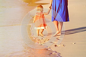 Mother and little daughter walking on beach