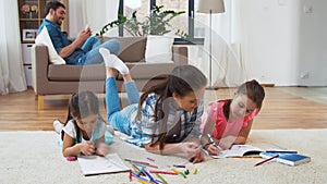 Mother with little daughters drawing at home