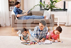 Mother with little daughters drawing at home