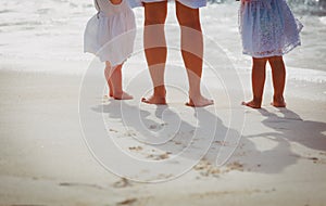 Mother with little daughters walk on sand beach