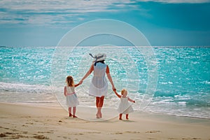 Mother with little daughters walk on sand beach photo