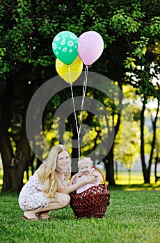 Mother with little girl on background of green trees. Baby girl