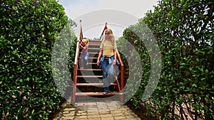 Mother Little Girl Climb down Stairs in Hedge Labyrinth in Park