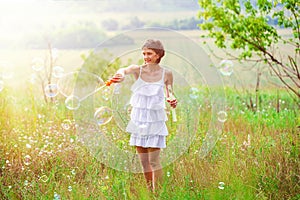 Mother and little girl daughter child blowing soap bubbles outdoor. Parent and kid having fun on meadow. Happy and