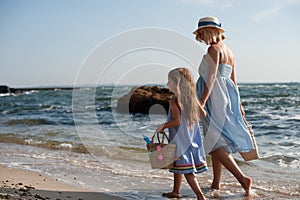 Mother and little girl hiking near sea