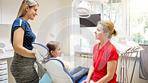 Mother and girl listening pediatric dentist in clinic