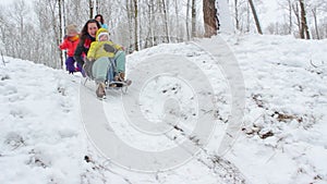 Mother with a little girl rides a sled from a hill