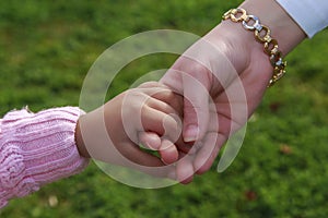 Mother and little girl's hands with green garden background