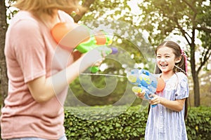 Mother and little girls playing water guns in the park