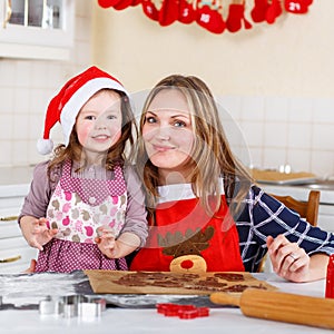 Mother and little kid girl baking gingerbread cookies for Christ