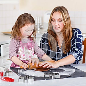 Mother and little kid girl baking gingerbread cookies for Christ