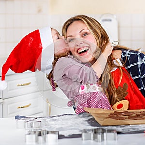 Mother and little kid girl baking gingerbread cookies for Christ