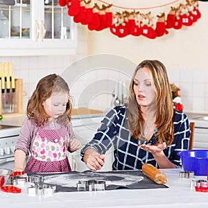 Mother and little kid girl baking gingerbread cookies for Christ