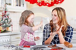 Mother and little kid girl baking gingerbread cookies for Christmas