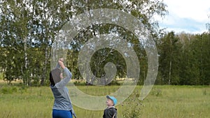 Mother with little son flying kite outdoor