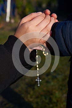 Mother and little son hold each other`s hand with a rosary photo