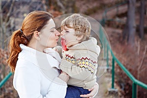 Mother and little son in park or forest, outdoors. Hugging and having fun together. Happy toddler boy and young mum, kid