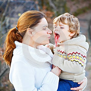 Mother and little son in park or forest, outdoors. Hugging and having fun together. Happy toddler boy and young mum, kid