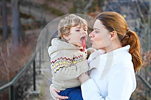 Mother and little son in park or forest, outdoors. Hugging and having fun together. Happy toddler boy and young mum, kid