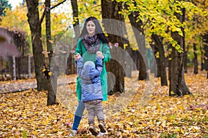 Mother with little son plays in autumn park