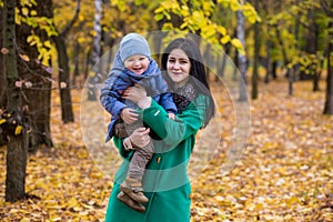 Mother with little son plays in autumn park