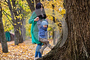 Mother with little son plays in autumn park