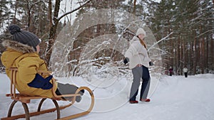 mother and little son are spending time and having fun in winter forest in weekend, happy family