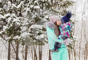 Mother and little toddler girl walking in the winter forest and having fun with snow. Family enjoying winter. Christmas