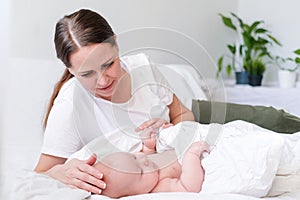 Mother love. Caucasian young brunette woman mom looking to her little cutest baby lying in bed. Infant child. Family