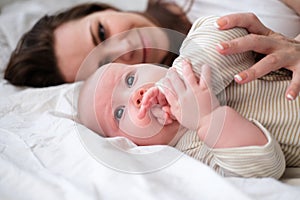 Mother love. Caucasian young brunette woman mom looking to her little cutest baby lying in bed. Infant child. Family