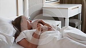 Mother lying on bed with her sleeping child, at home.