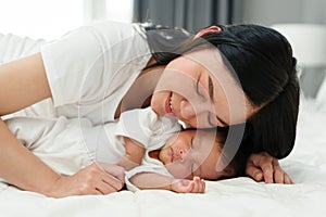 mother lying down and loving her newborn baby on bed