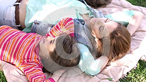 Mother lying on the grass with the girls under a blossoming Apple tree. parents and children