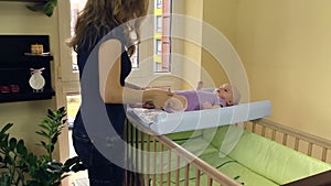 Mother make therapeutical massage for child lie on swaddle board