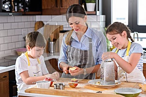 Mother making apple pie with children at home kitchen