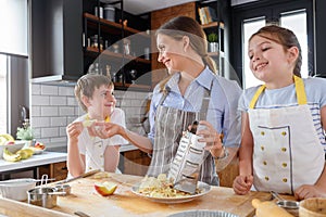 Mother making apple pie with children at home kitchen