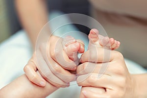 Mother making baby feet massage for newborn infant child. Mom massaging legs of small baby son.Children healthcare and happy