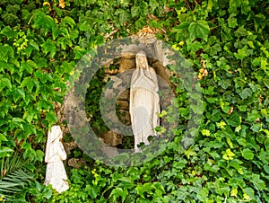 Mother Mary in a Prayer Pose With a Child surrounded by Greenery