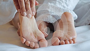 Mother massages her baby`s feet close up.